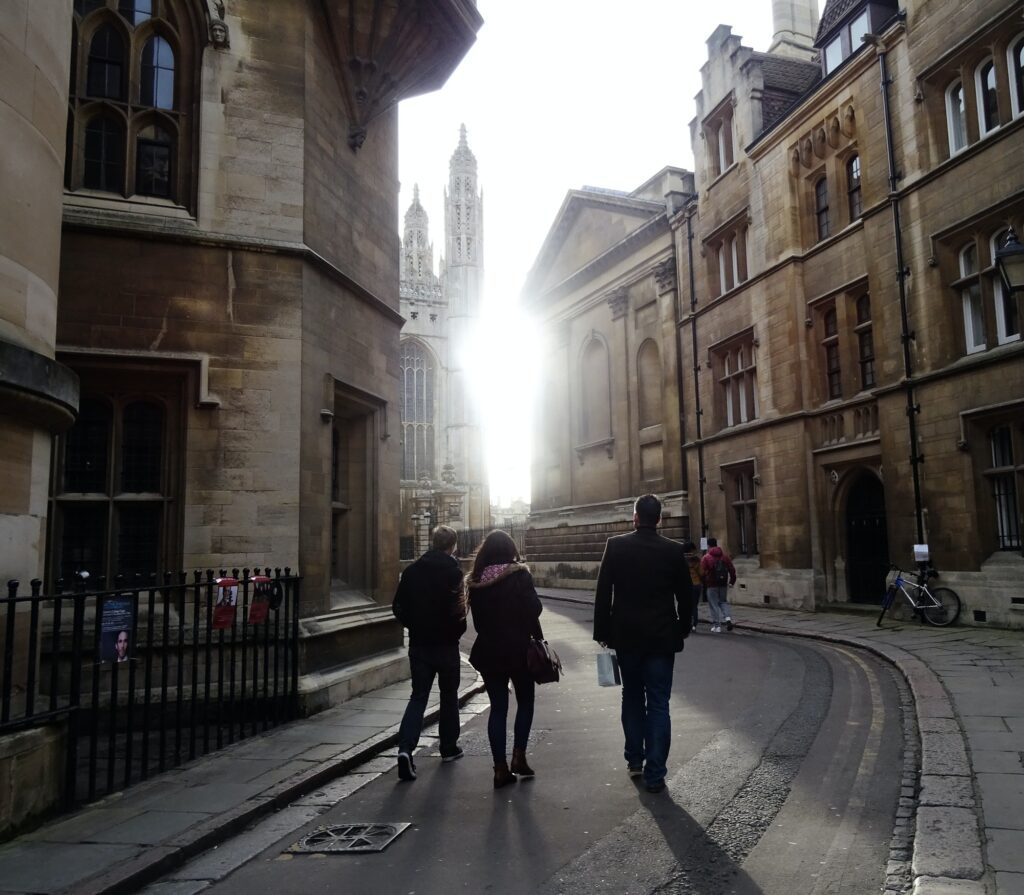 People walking on a street towards bright light, Cambridge, UK.