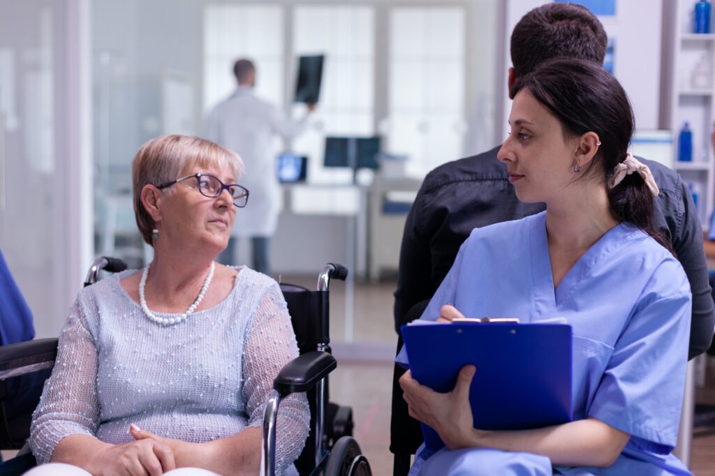 Medical nurse explaining diagnosis to handicapped senior woman patient
