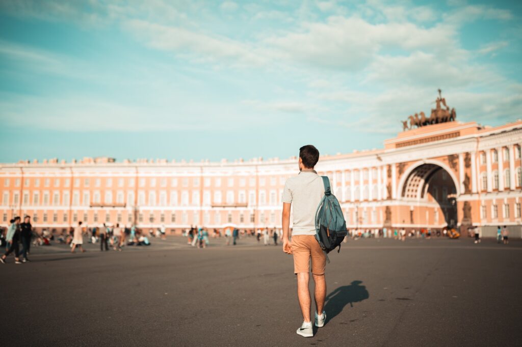 Young man from behind standing on Palace square in Saint-Petersburg, Russia at hot summer day