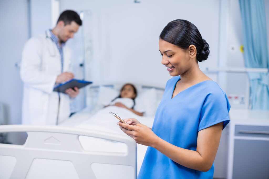 Smiling nurse using mobile phone