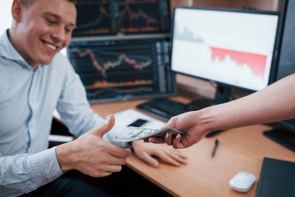 Money makes everyone happy. Day of salary in the modern office with screens with graphs on them