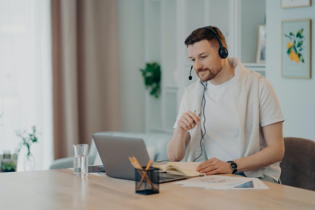 European male student learns foreign languages online has video lesson uses modern headset